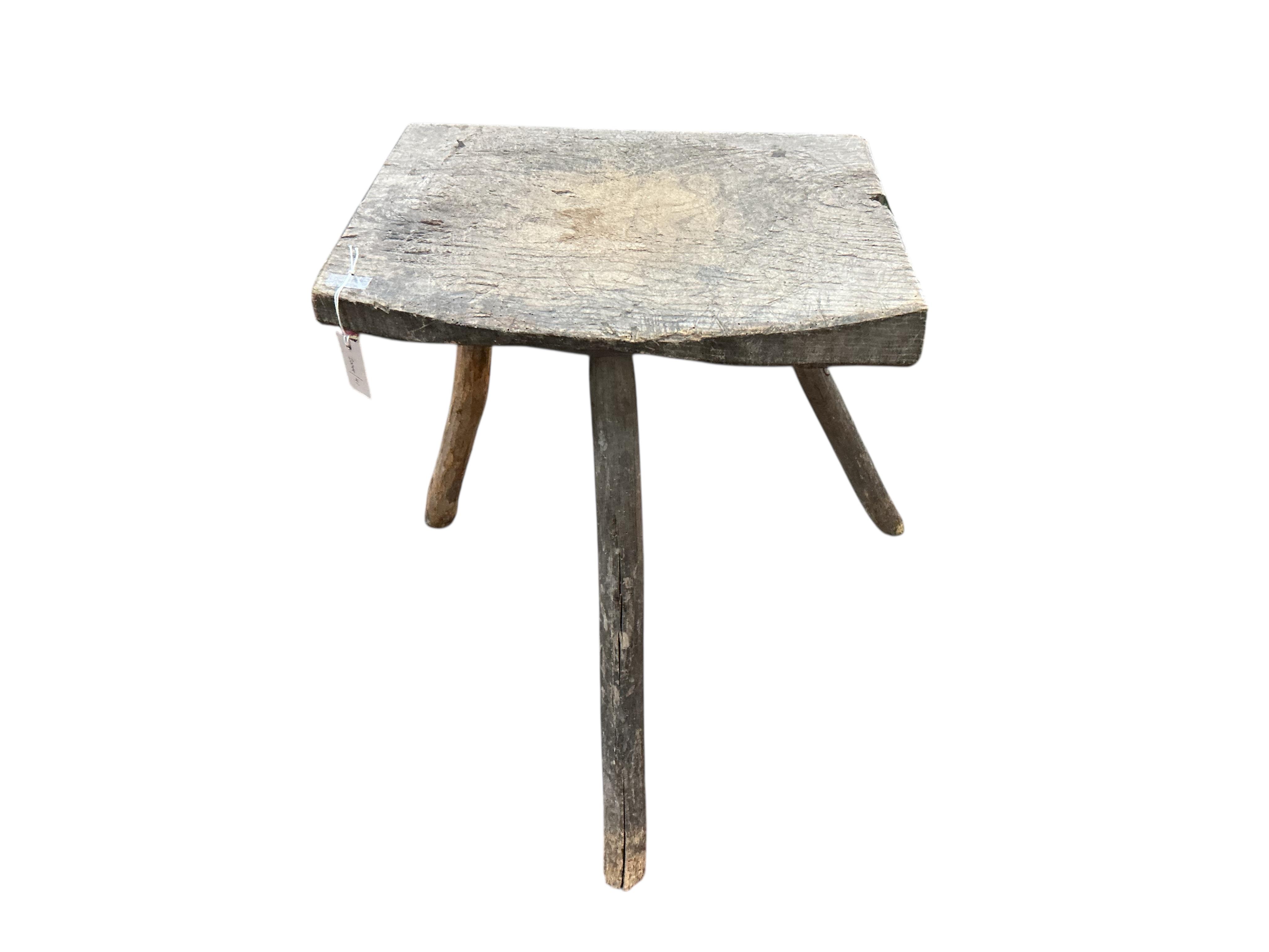 A French Provincial elm three legged block, width 54cm, depth 41cm, height 73cm